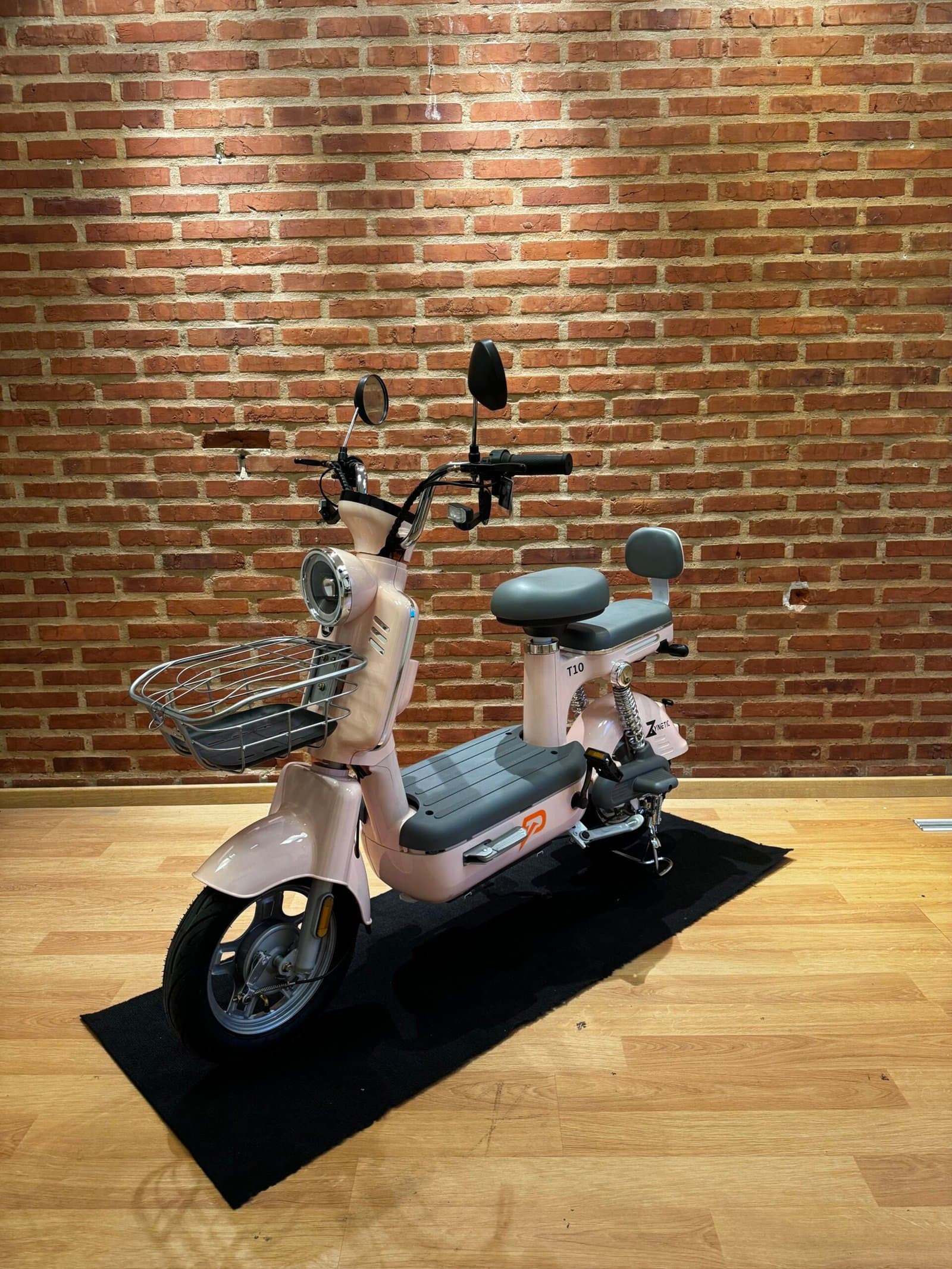 Bicicleta eléctrica Zynetic Elea rosa compacta con canasto delantero, vista tres cuartos